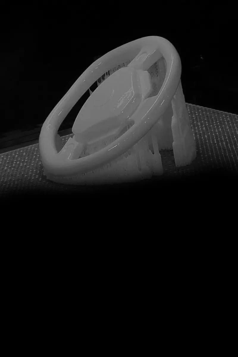 3D-gedrucktes Bauteil eines Lenkrads mit Stützstrukturen auf einer texturierten Oberfläche.