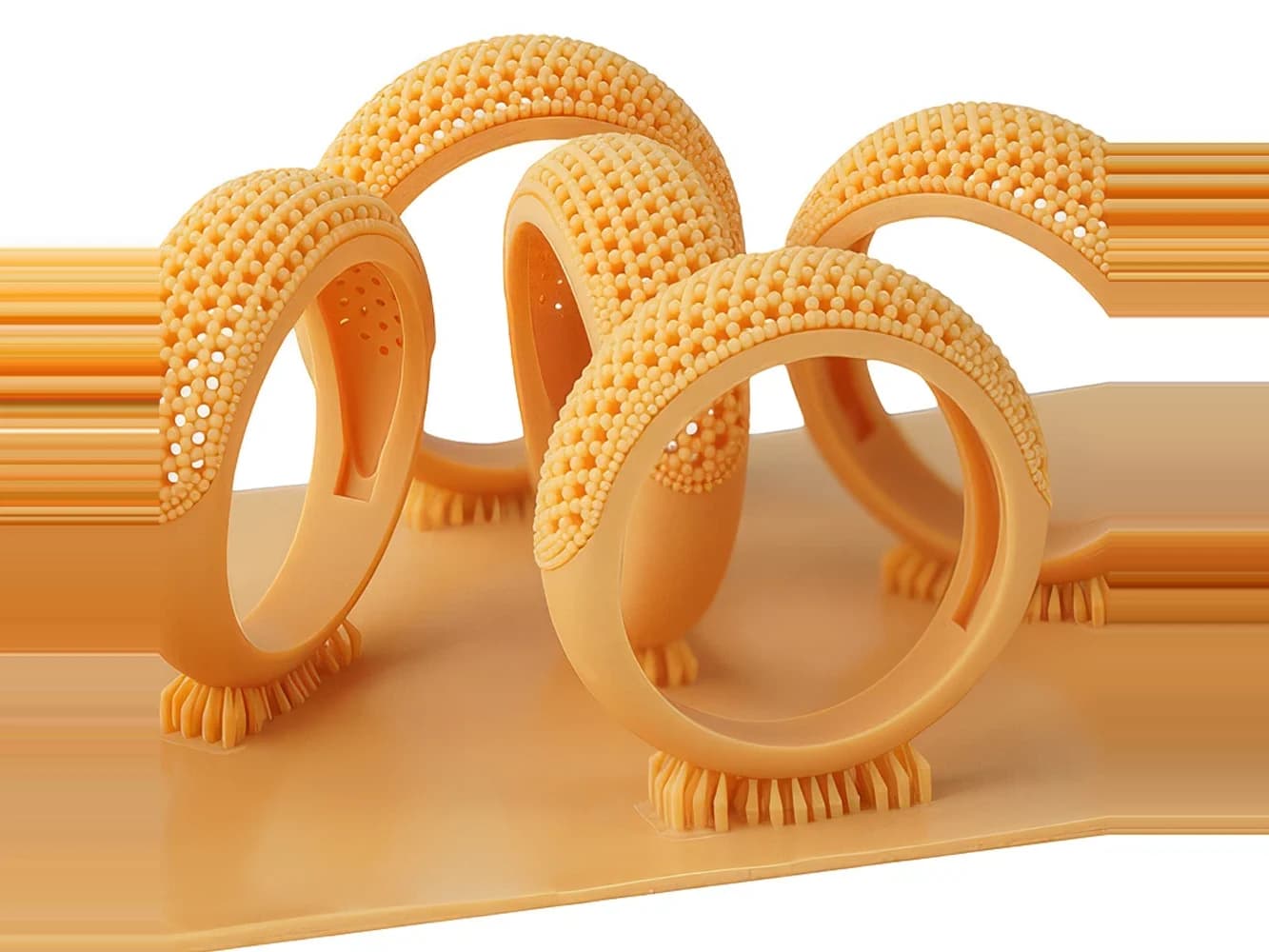 Mehrere orangefarbene Ringe mit perlenbesetzter Oberfläche aus RC800, noch auf der Druckplatte.