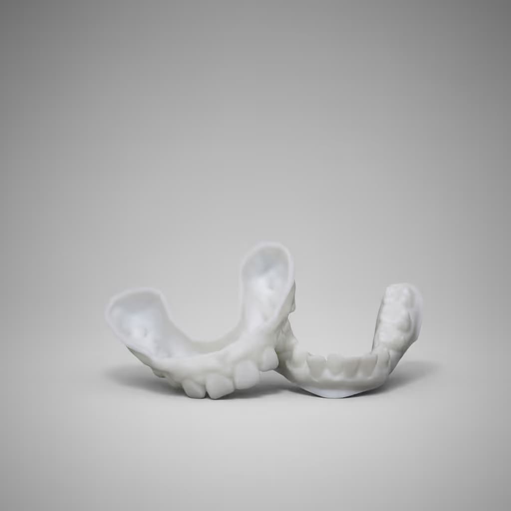 Weißes 3D-gedrucktes Modell eines menschlichen Ober- und Unterkiefers auf grauem Hintergrund.