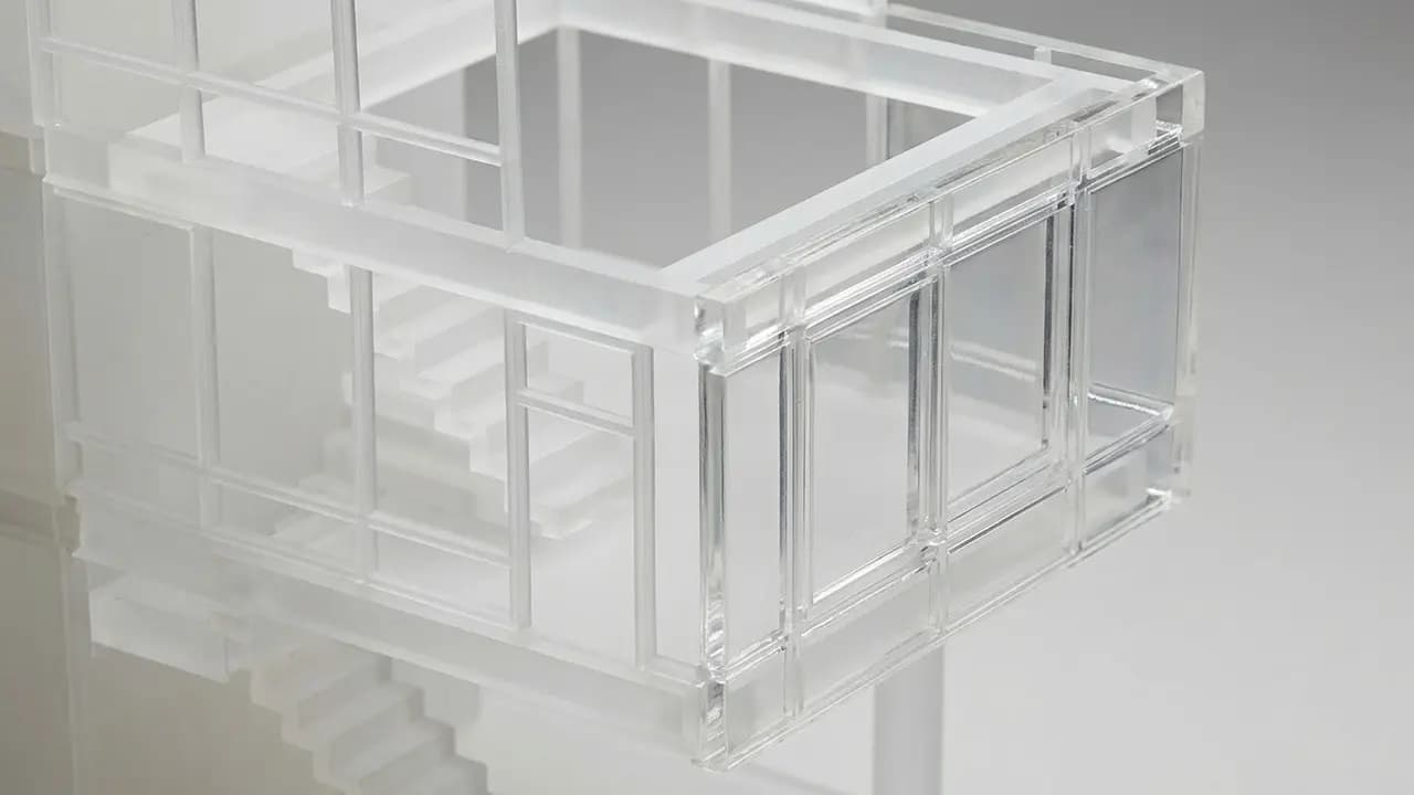 Ein transparentes, modernes Architekturmodell eines Hauses mit Treppe und großen Fenstern.