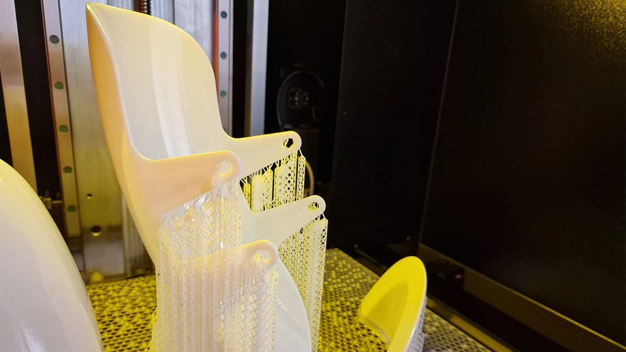 3D-Drucker mit gedruckten rosa Objekten, die an Stützstrukturen im Druckbereich hängen.