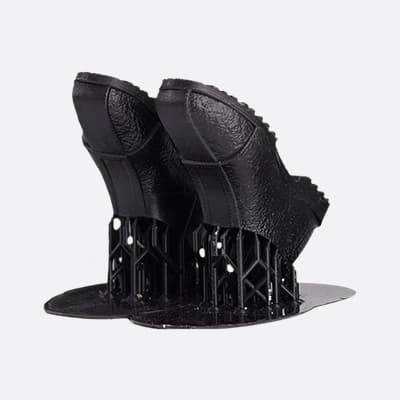 Ein Paar schwarze, strukturierte Schuhspitzen, die auf einem runden Sockel stehen.