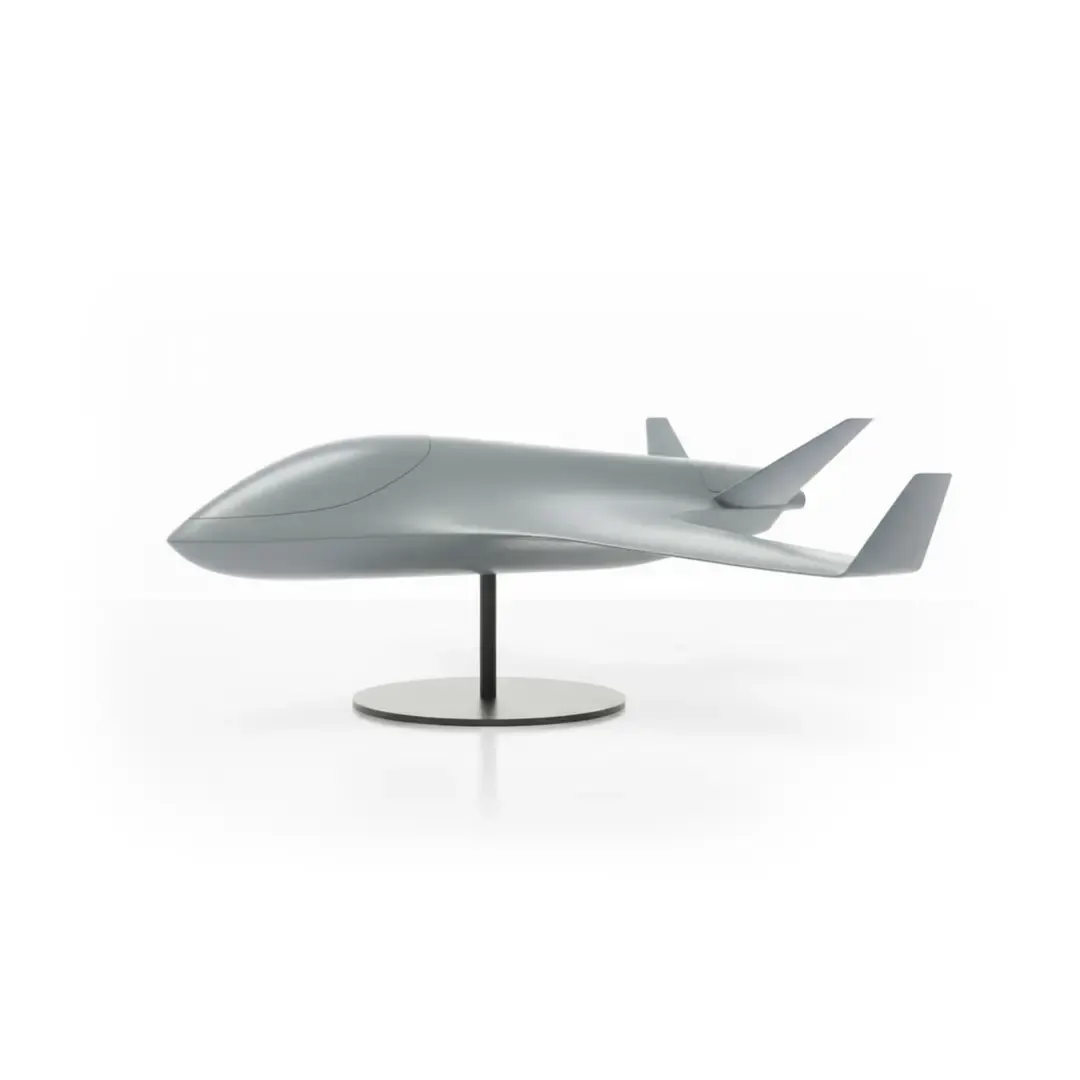 Modell einer grauen, futuristischen Drohne mit Flügeln auf einem Ständer vor weißem Hintergrund.